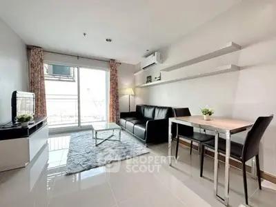 Modern living room with sleek furniture and large window offering natural light.