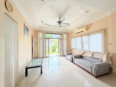 Spacious living room with modern ceiling fan and large windows overlooking garden
