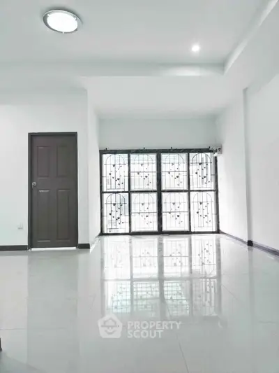 Spacious modern interior with glossy floors and secure window grills in a bright room.