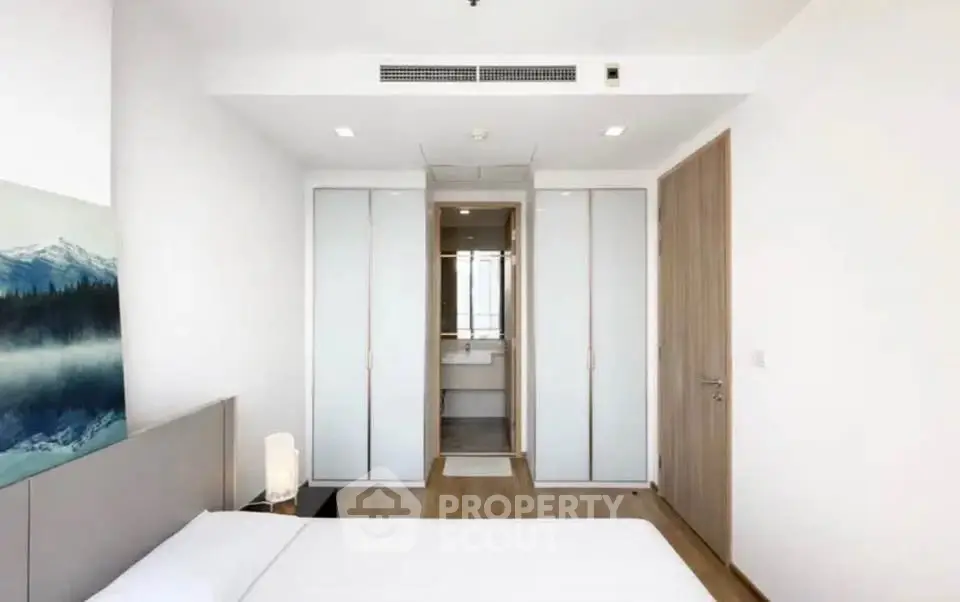 Modern bedroom with minimalist design and ensuite bathroom in a stylish apartment.