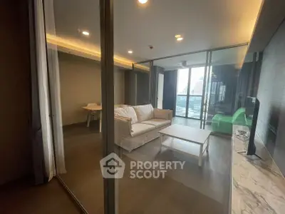 Modern living room with glass walls and city view, featuring cozy sofa and sleek design.