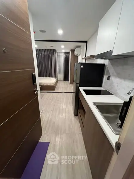 Modern studio apartment with compact kitchen and cozy bedroom area.