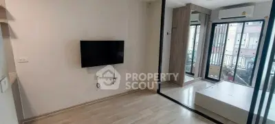 Modern living room with wall-mounted TV and large windows offering natural light.