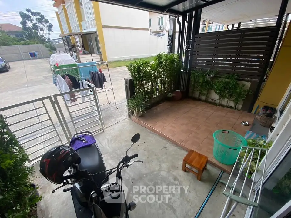 Charming outdoor patio with greenery and motorbike parking in a residential area.