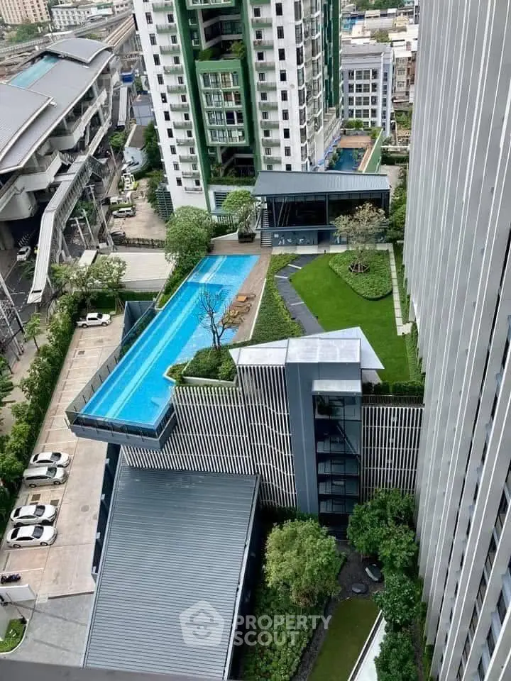Stunning aerial view of modern high-rise building with rooftop pool and lush garden in urban setting.