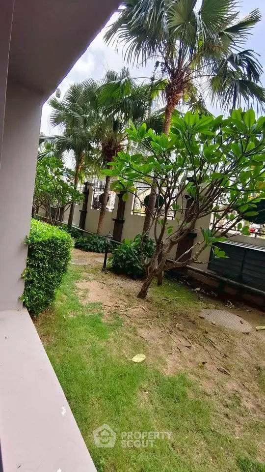 Lush garden view with tropical trees and manicured lawn in a serene residential setting.