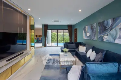 Luxurious living room with modern decor, large TV, and pool view through sliding glass doors.