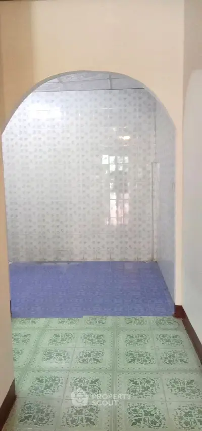 Spacious interior with unique patterned flooring and archway, ideal for creative design.