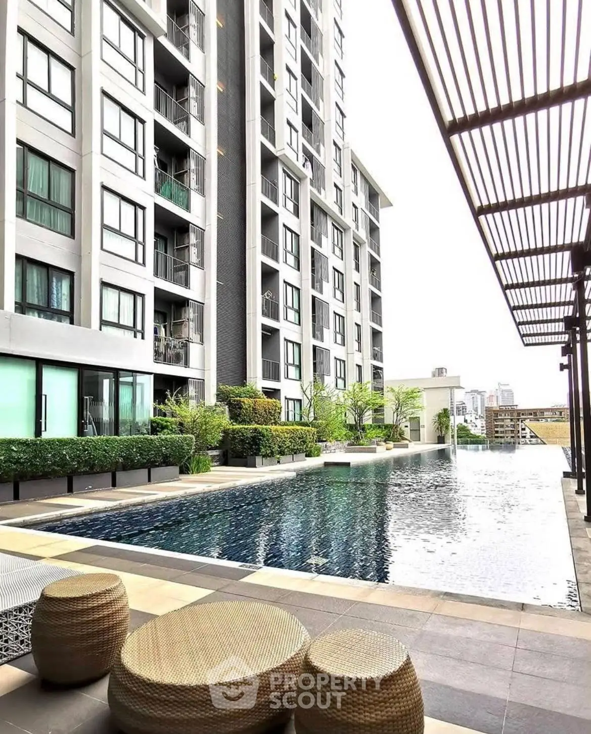 Luxurious apartment building with modern poolside area and city view.