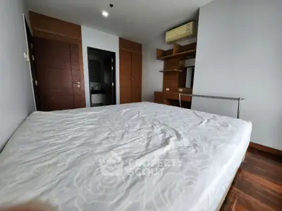Spacious bedroom with modern wooden accents and built-in air conditioning unit.