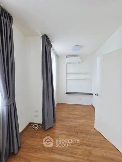 Bright and airy room with wooden flooring and modern air conditioning, perfect for a cozy home office or study.