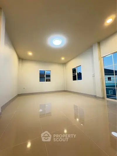 Spacious empty room with glossy tiled floor and large windows