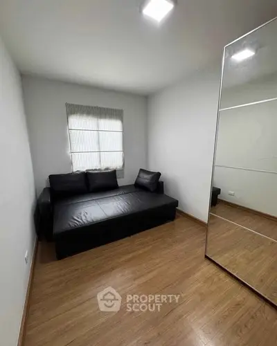 Cozy small room with wooden flooring and black leather sofa, perfect for a compact living space.