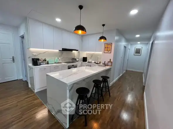 Modern kitchen with sleek white cabinets and marble island in open layout.