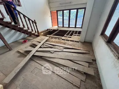 Spacious interior with wooden staircase and large windows, ideal for renovation projects.
