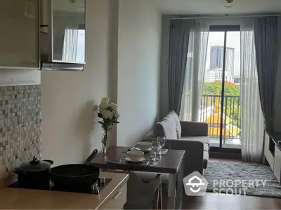 Modern apartment with open kitchen and cozy living area, featuring a balcony with city view.