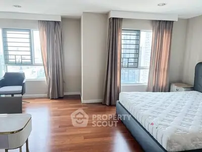 Spacious bedroom with large windows and hardwood floors in modern apartment.