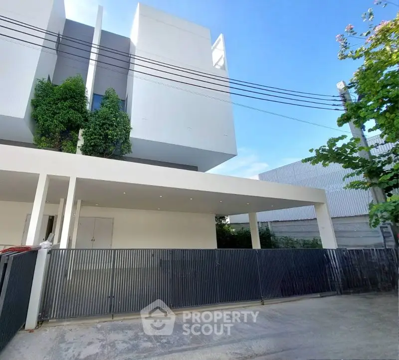 Modern white building exterior with sleek design and spacious parking area.
