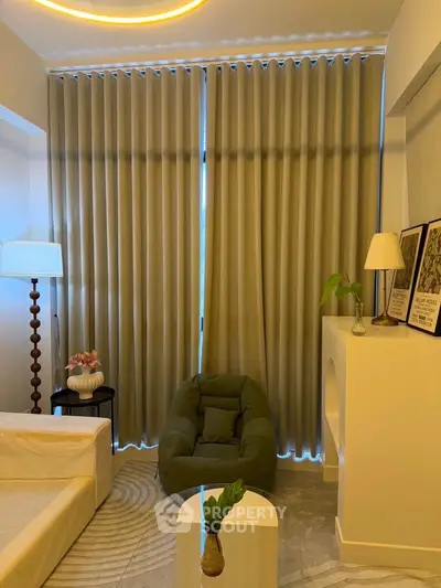 Cozy living room with modern decor, featuring a plush armchair, elegant curtains, and stylish lighting.