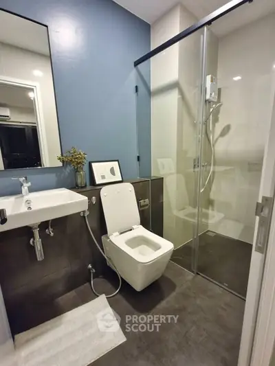 Modern bathroom with sleek design, featuring glass shower and stylish fixtures.
