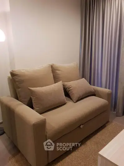 Cozy living room with a comfortable beige sofa and elegant curtains, perfect for relaxation.