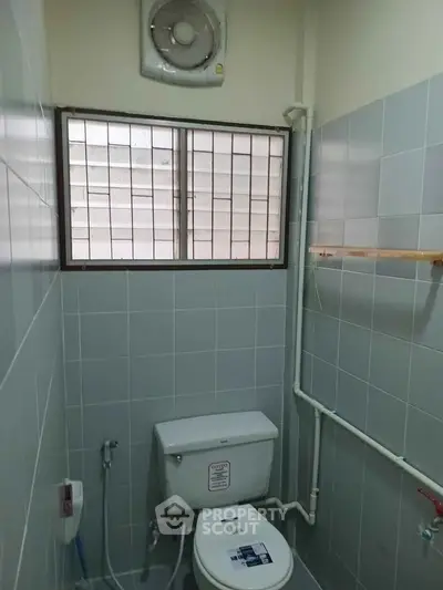 Compact bathroom with tiled walls and window ventilation