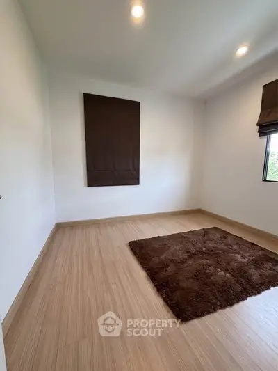 Minimalist room with wooden flooring and brown rug, perfect for cozy living.