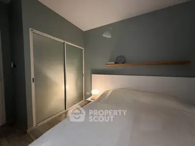 Cozy bedroom with minimalist design and soft lighting, featuring a sliding door closet and modern decor.