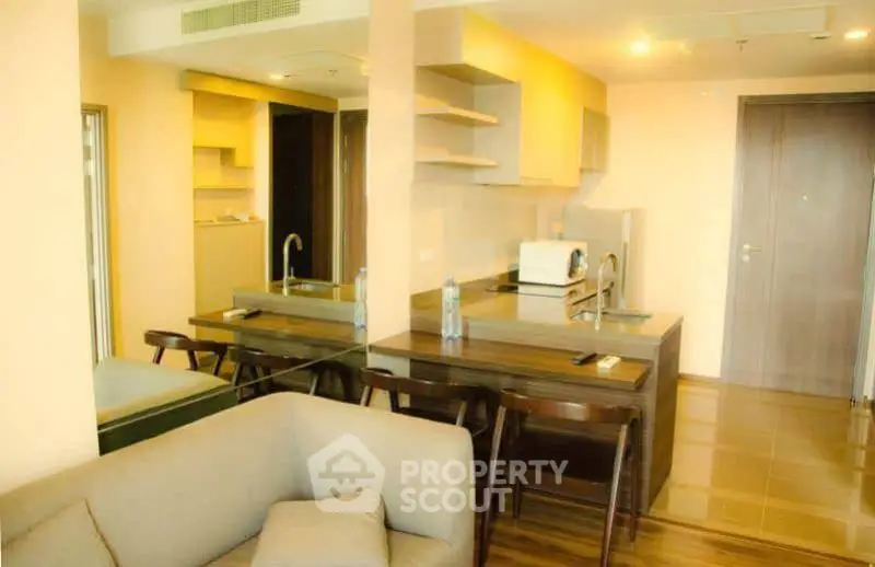 Modern open-layout kitchen and living area with sleek furniture and warm lighting.