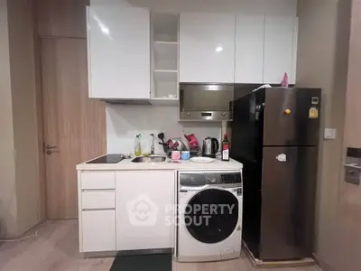 Modern compact kitchen with sleek appliances and stylish cabinetry in a cozy apartment.