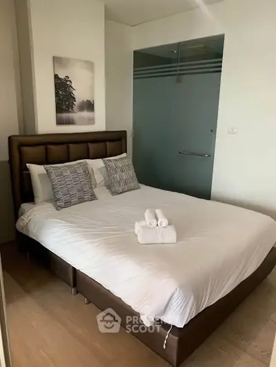 Cozy bedroom with modern decor and glass door, perfect for relaxation.