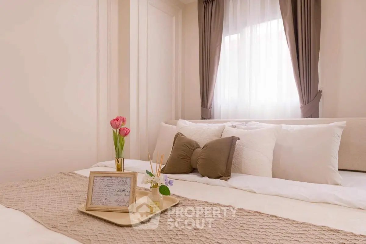 Cozy bedroom with elegant decor and soft lighting, featuring plush pillows and a decorative tray on the bed.