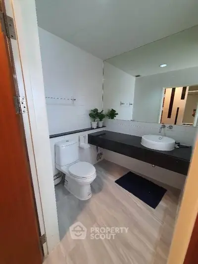 Modern bathroom with sleek design, featuring a white toilet, stylish sink, and elegant flooring.