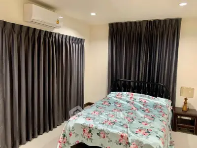 Cozy bedroom with floral bedding and dark curtains, featuring air conditioning.