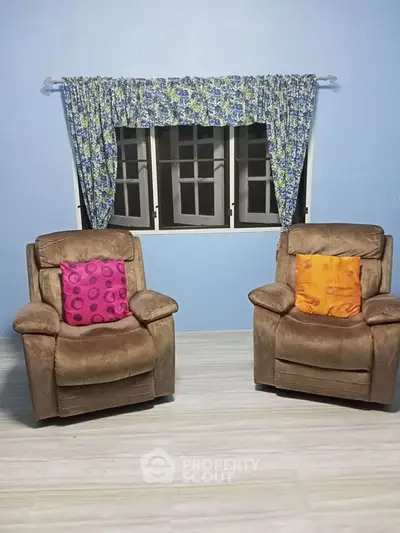 Cozy living room with two plush armchairs and floral curtains