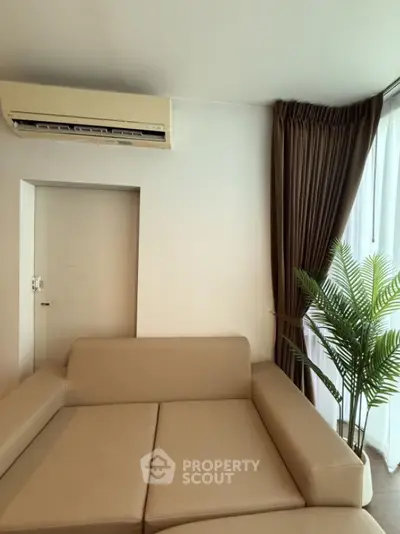 Modern living room with beige sofa, air conditioner, and elegant curtains