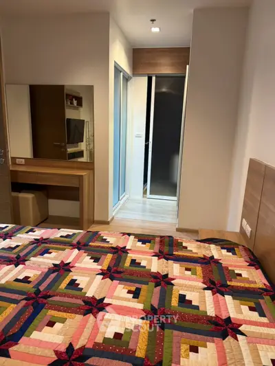 Cozy bedroom with colorful quilt and modern wooden furniture, perfect for relaxation and comfort.