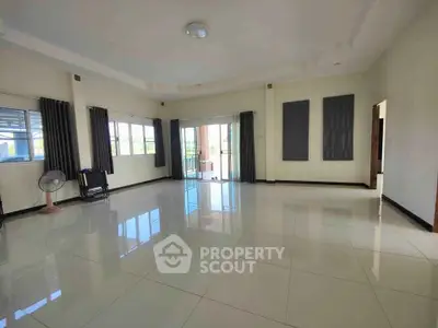 Spacious and bright living room with large windows and glossy tiled floors.