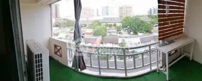 Spacious balcony with city view and green flooring, perfect for relaxation.