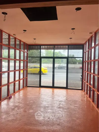 Spacious commercial space with large glass windows and street view, ideal for retail or office setup.