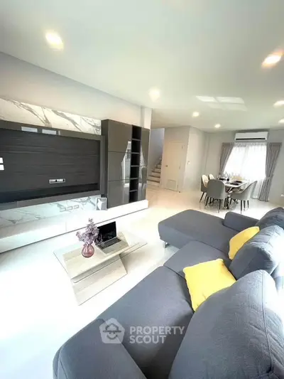 Spacious modern living room with stylish furniture and open dining area, perfect for family gatherings.