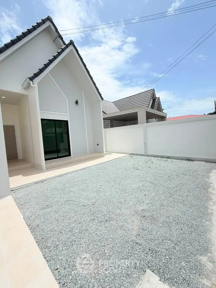 Modern single-story house with spacious gravel driveway and sleek exterior design.