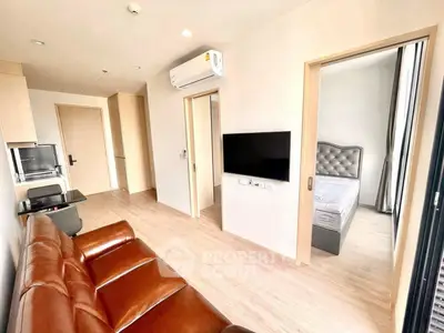 Modern apartment interior with leather sofa, wall-mounted TV, and cozy bedroom view.