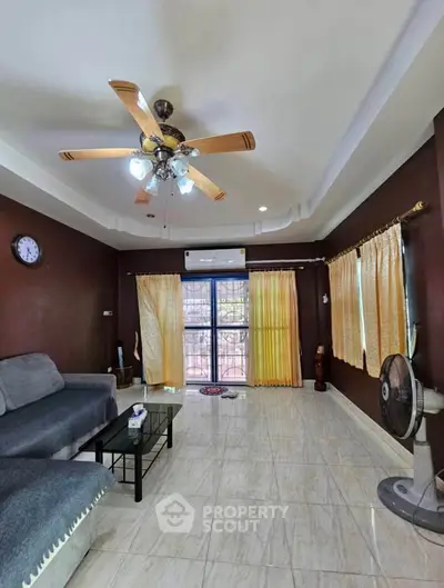 Spacious living room with modern ceiling fan and large windows for natural light.