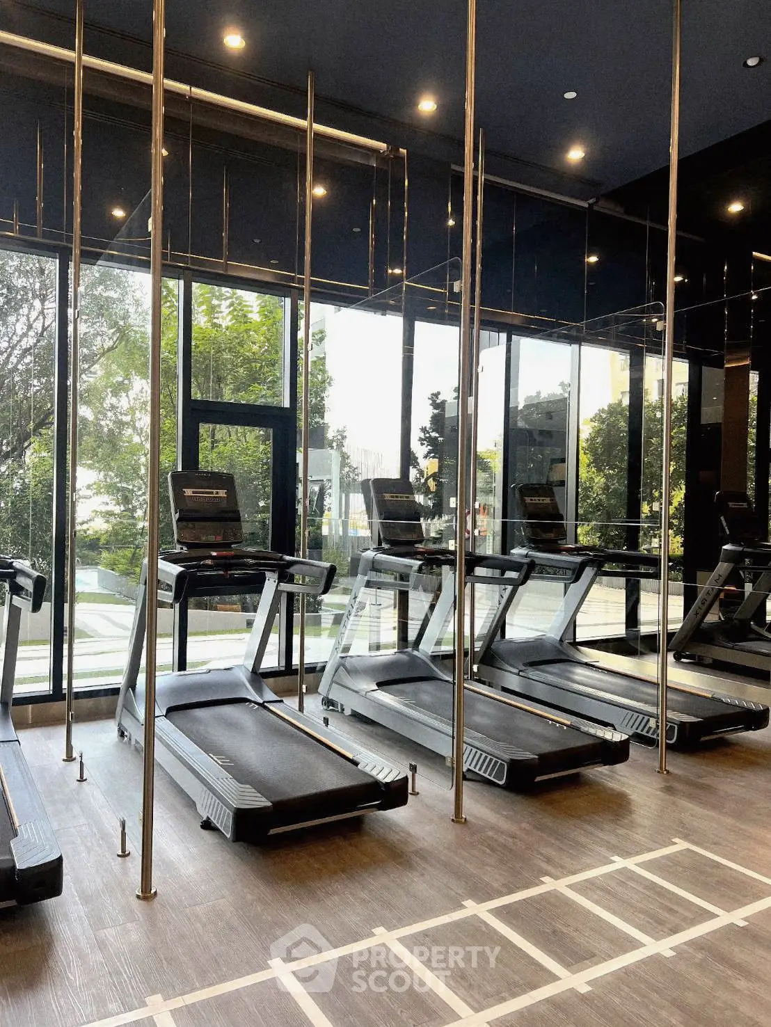 Modern gym with treadmills and large windows overlooking greenery