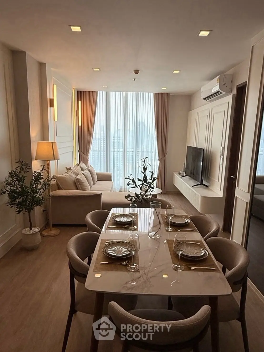 Elegant living room with dining area, featuring modern decor and large windows for natural light.
