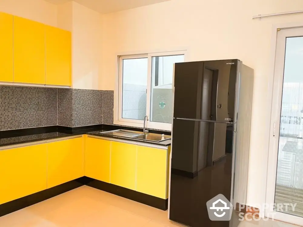 Bright kitchen with vibrant yellow cabinetry, modern appliances, and ample natural light, perfect for culinary enthusiasts.