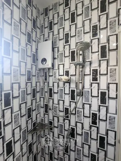 Modern bathroom with stylish black and white tile design and shower fixtures.