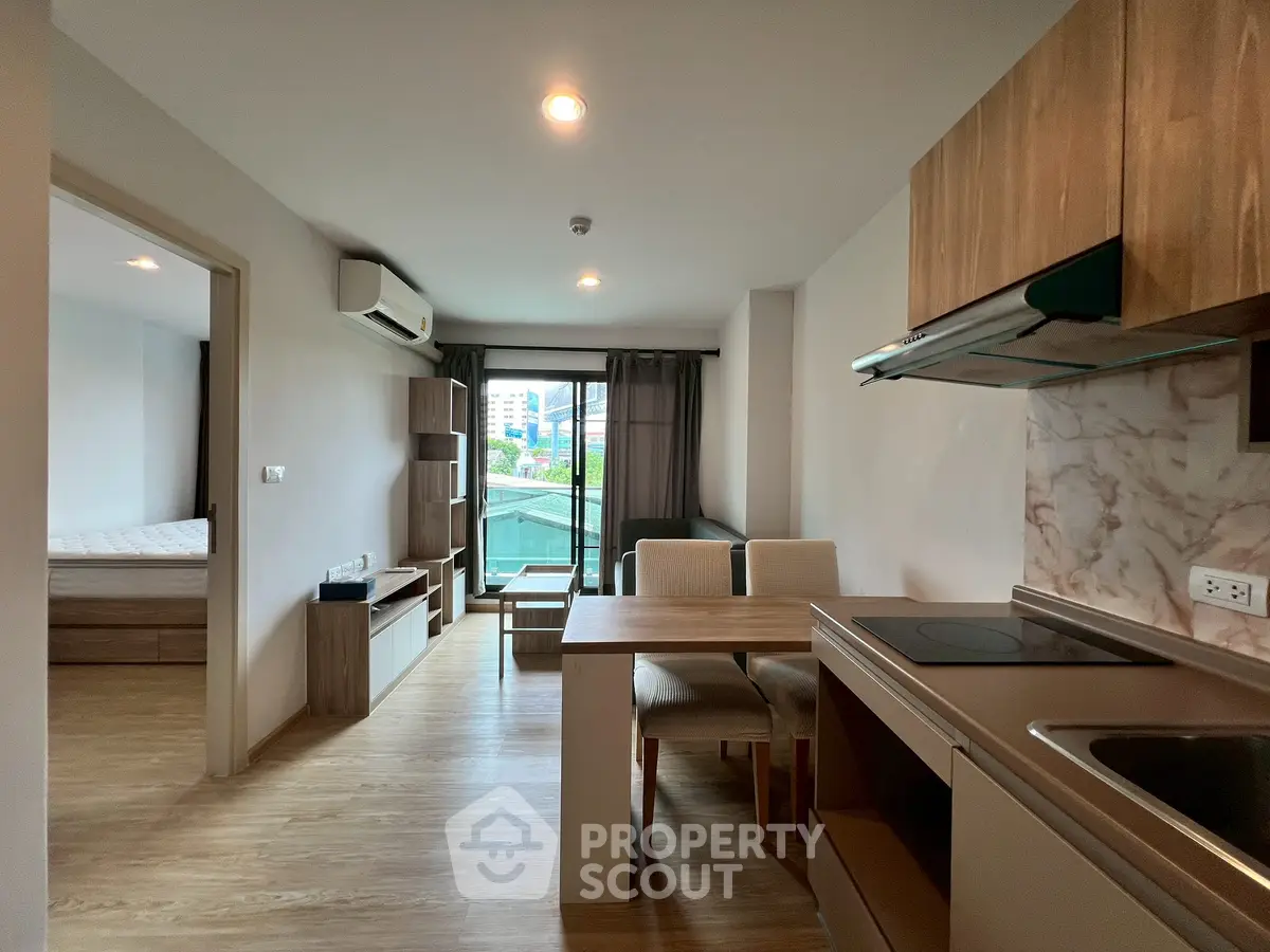 Modern open-plan living room with kitchen and dining area, featuring sleek wooden finishes.