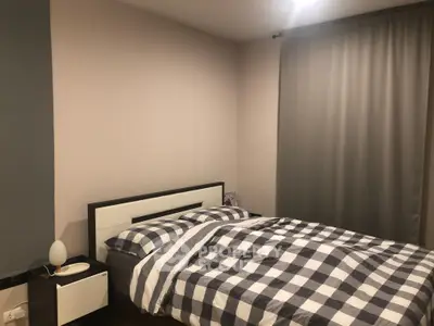 Cozy bedroom with a large bed covered in checkered linens, sleek side tables, and elegant gray curtains, perfect for restful nights.
